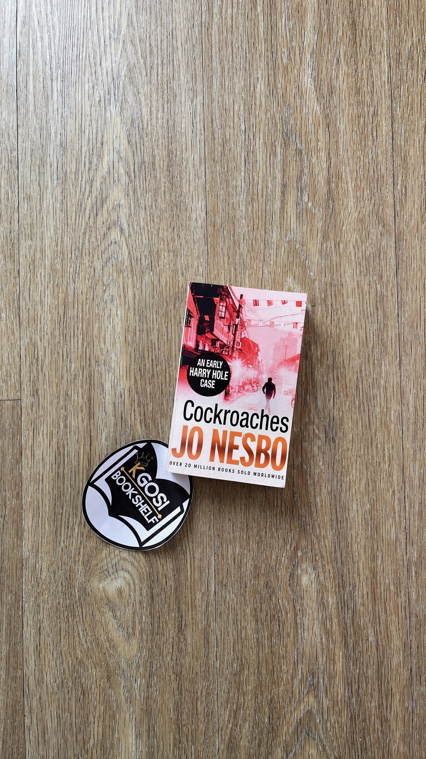 Book 'Cockroaches' by Jo Nesbo and a badge on a wooden surface