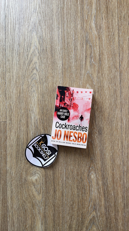 Book 'Cockroaches' by Jo Nesbo and a badge on a wooden surface