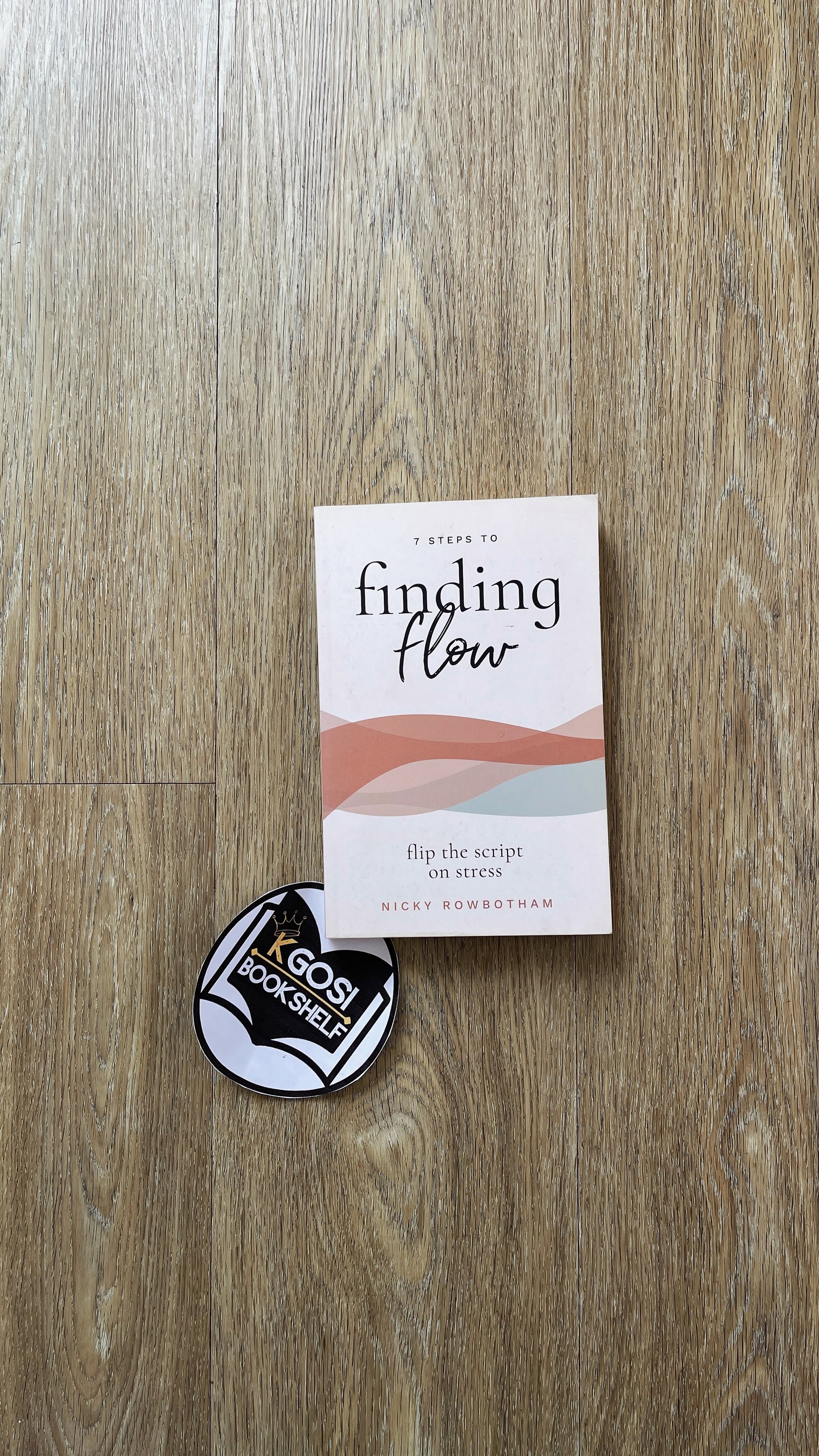 Book titled 'A Guide to Finding Flow' and a circular sticker on a wooden surface
