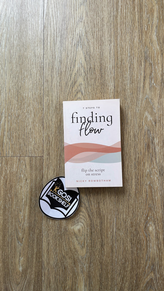 Book titled 'A Guide to Finding Flow' and a circular sticker on a wooden surface