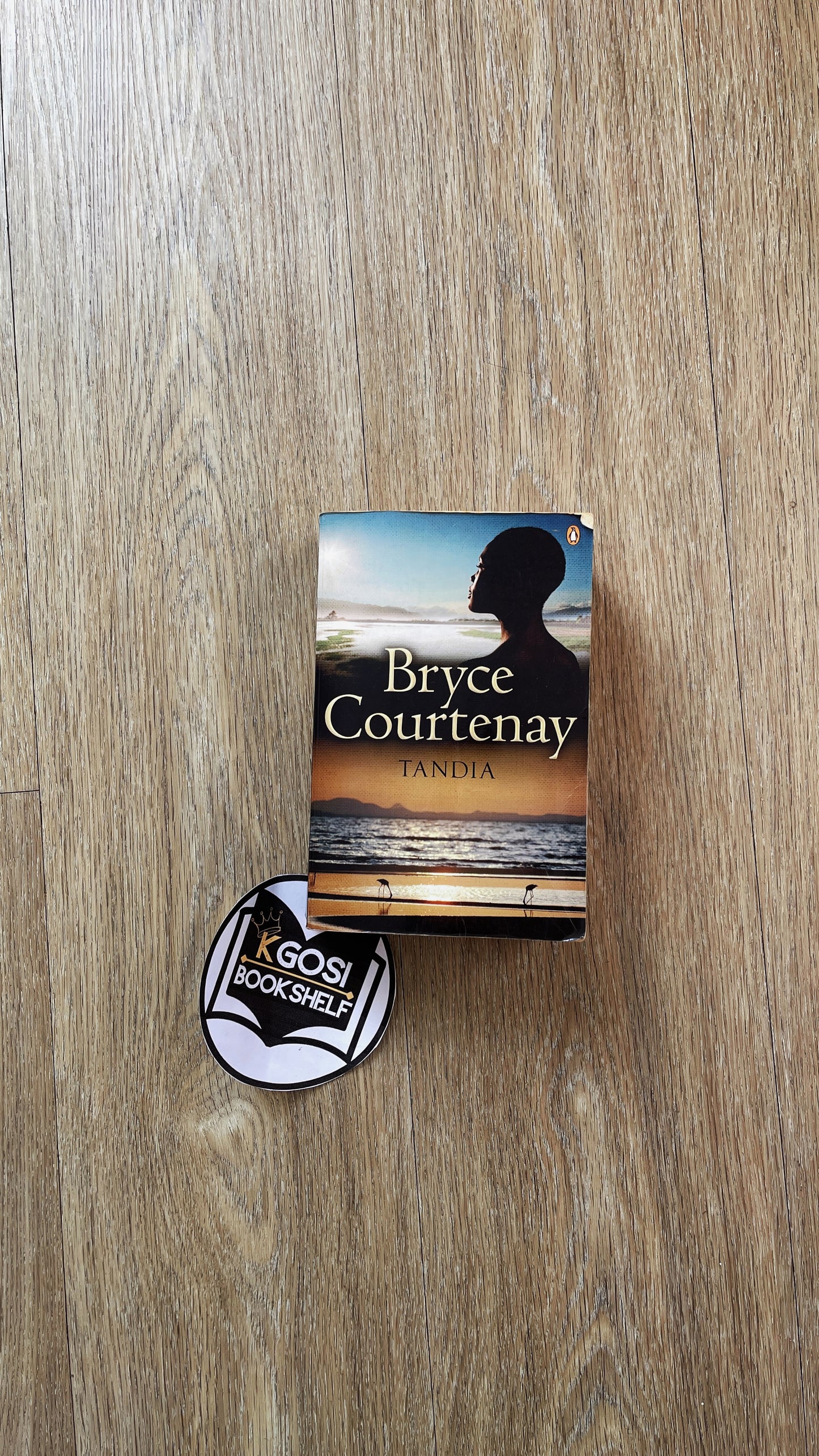 Tandia by Bryce Courtenay Book with a silhouette cover and a badge on a wooden surface