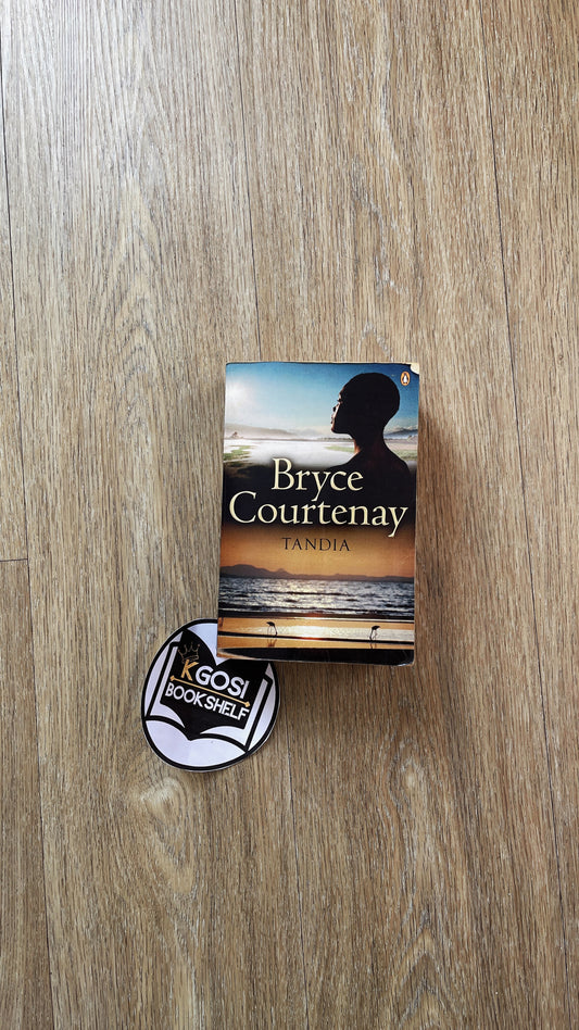 Tandia by Bryce Courtenay Book with a silhouette cover and a badge on a wooden surface